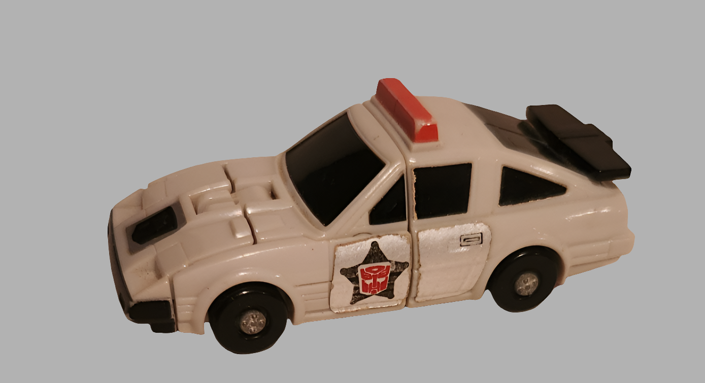 Vintage Transformers collectibles - white police car robot with black accents and red light on top